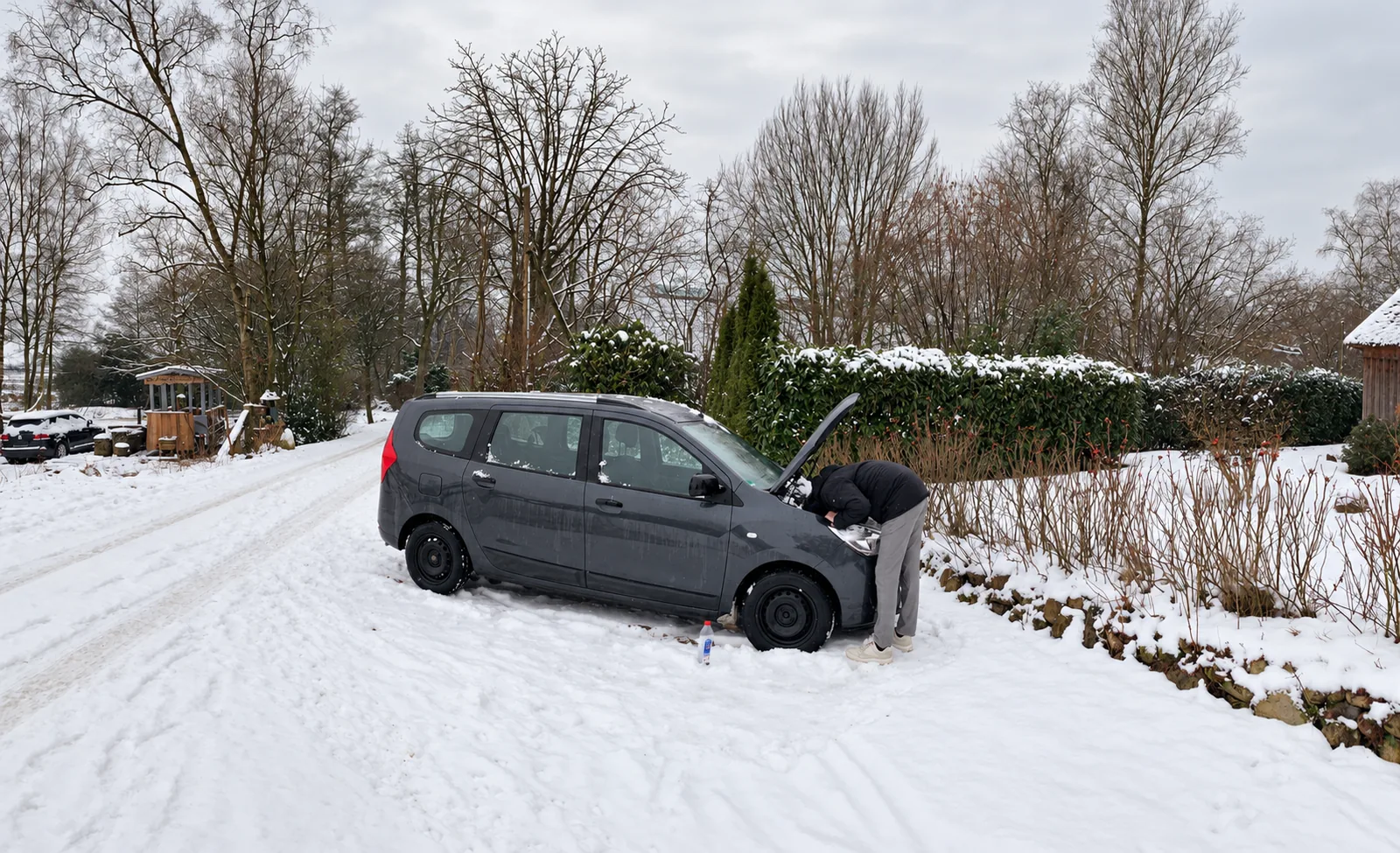 Auto mit geöffneter Motorhaube in einer verschneiten Einfahrt