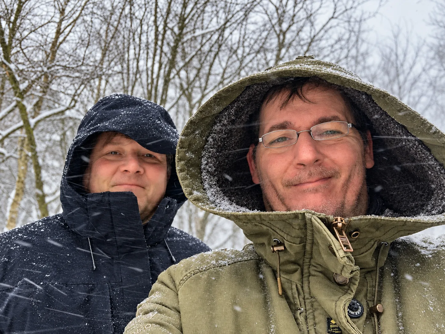 Zwei Musiker mit Kapuzen im verschneiten Wald